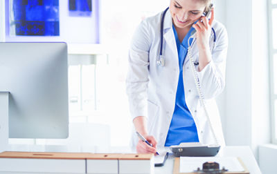 Picture of female staff member taking a phone call at a desk.