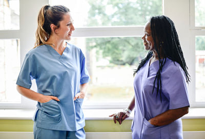 Picture of two female nurses talking to each other in a hospital hallway.